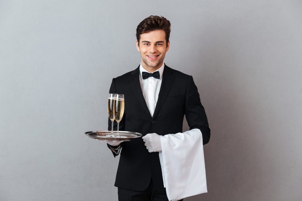 happy young waiter holding glass of champagne and towel.