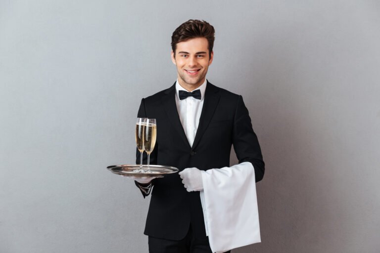 happy young waiter holding glass of champagne and towel.